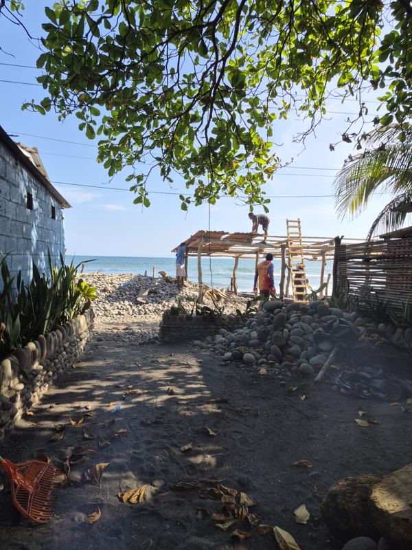 Wooden pergola beside black volcanic sand with rock barriers and ocean view