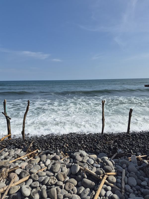 Rocky volcanic beach at El Sunzal with breaking Pacific waves and a clear sky