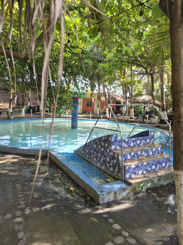 Children's pool with blue-tiled steps, shade structure and safety netting
