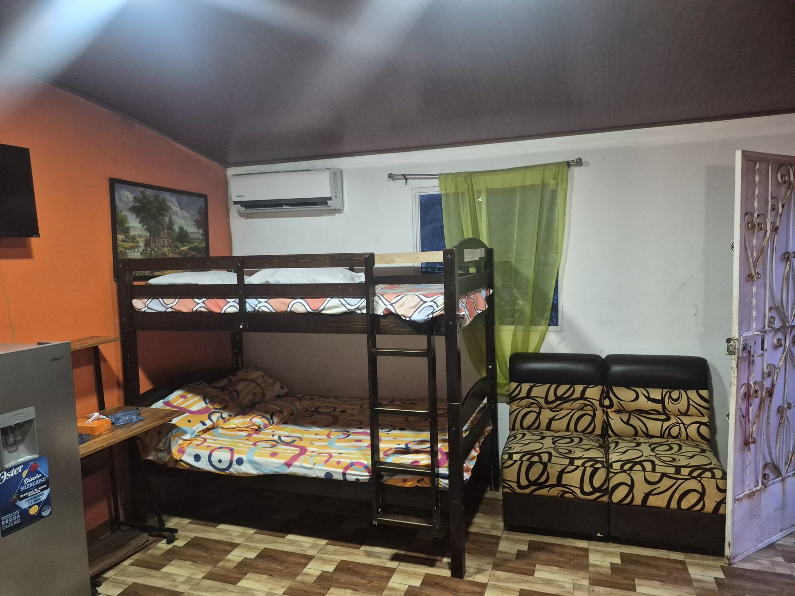 Room with a bunk bed and single bed, wall-mounted television and air conditioning